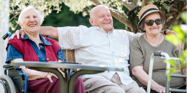 Three older persons sitting down and laughing