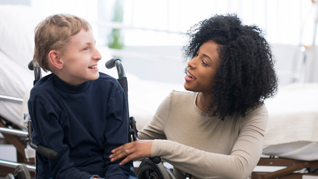 Picture1 Boy in wheel chair smiling with adult carer