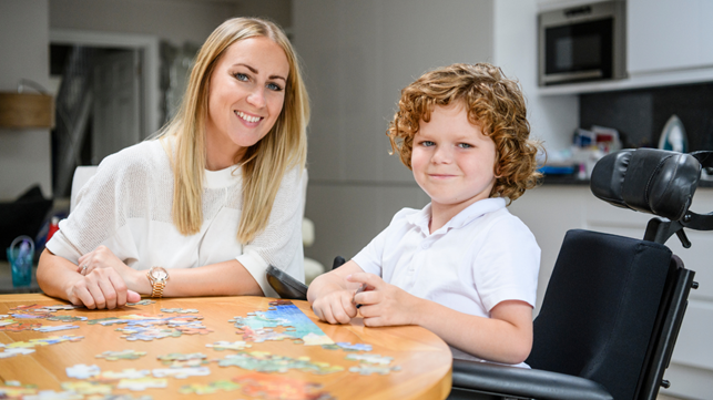 Picture1 Young boy in wheelchair with carer solving a jigsaw puzzle