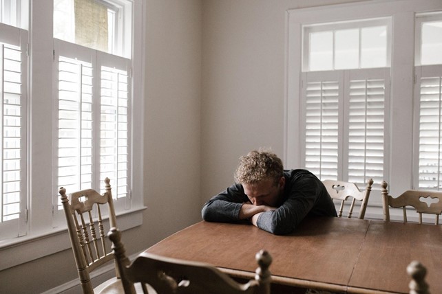 Man leaning into crossed arms across table