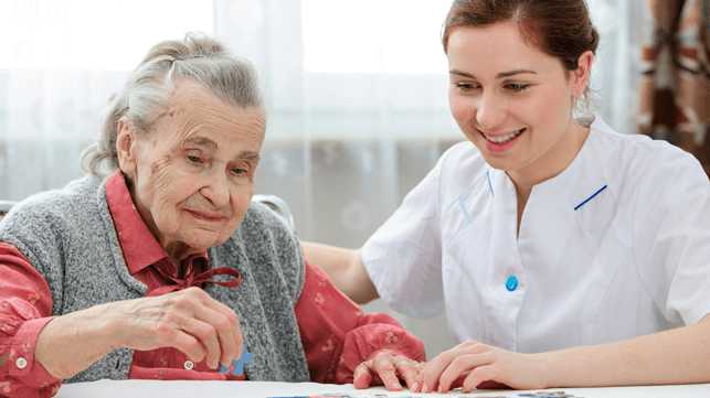 Senior female solving a jigsaw puzzle with a nurse