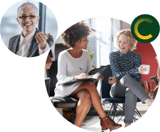 Older woman smiling while offering her left hand and two business women sitting down and laughing