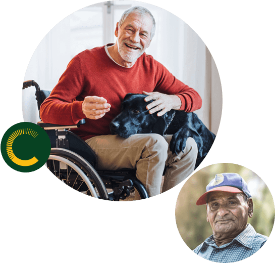 An older man in a wheelchair with his dog's head on his lap, smiling at the camera and an older man looking into the camera