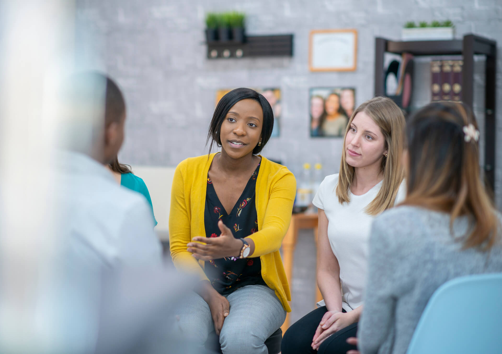 Three students sit on one side of a table studying. They are looking down at a notebook