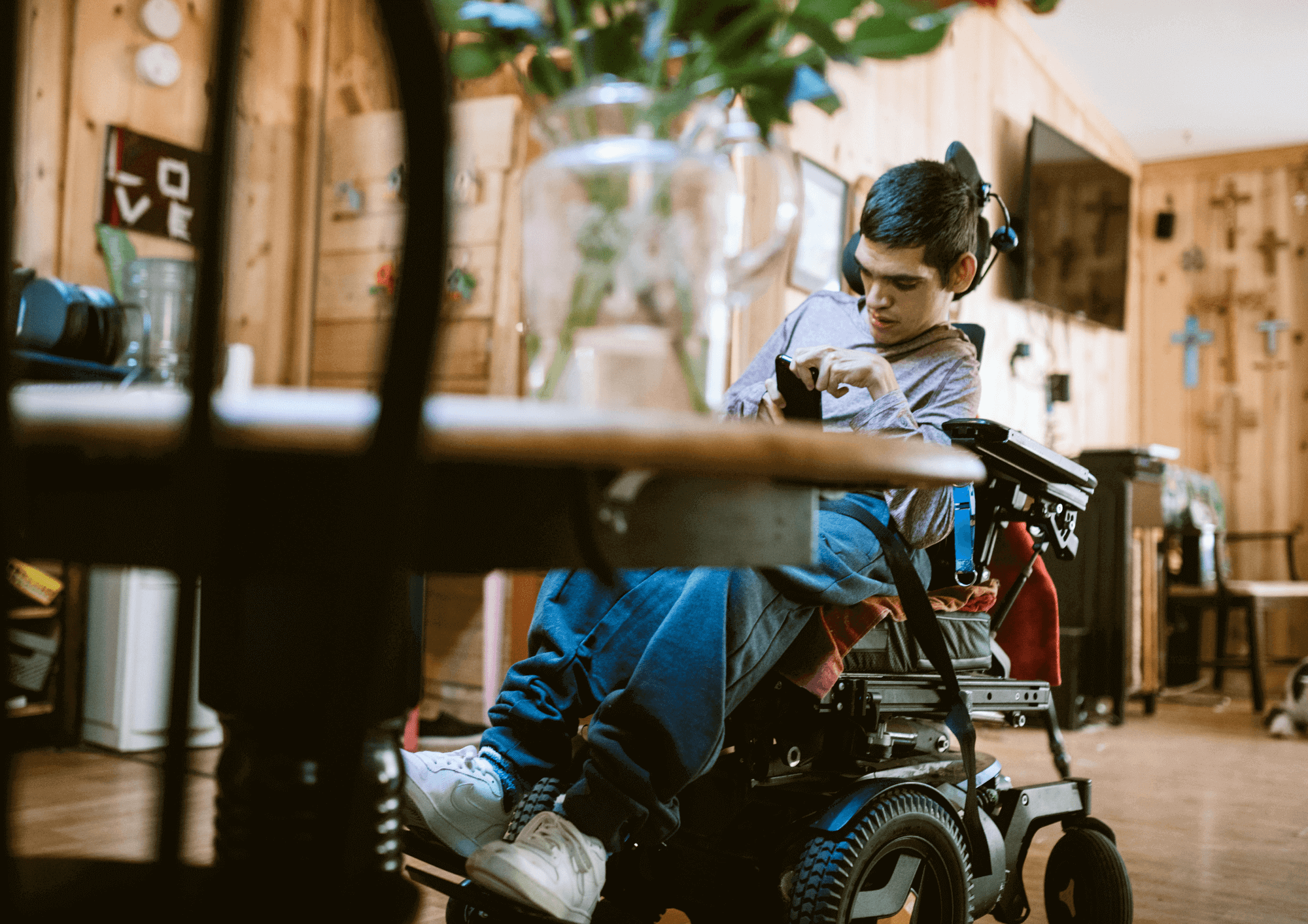 A disabled man in a wheelchair looks at his phone in the dining room.