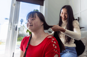 A woman stands next to and smiles at a disabled man in a wheelchair.